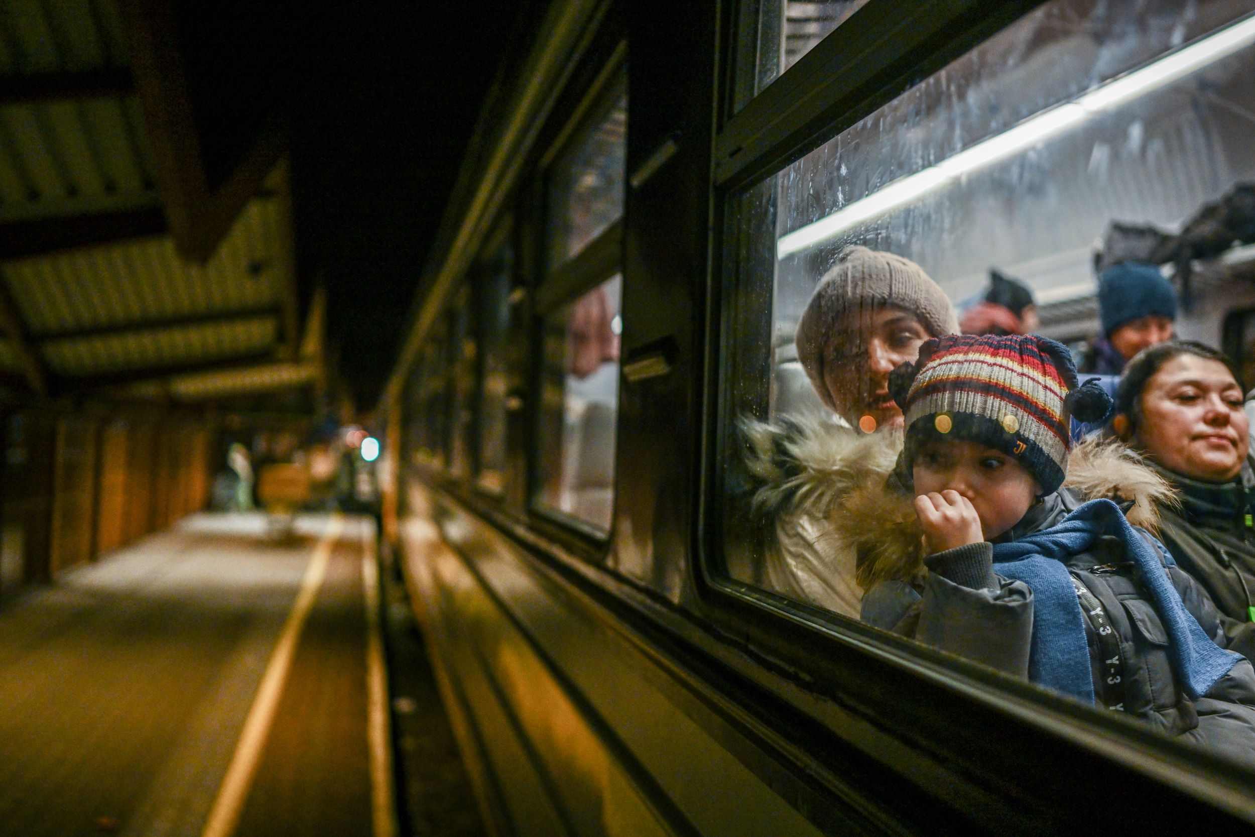 A woman and a child wait for a call to cross the passport control after arriving in a train from Kyiv at the Przemysl main train station on February 27, 2022 in Przemysl, Poland. [Omar Marques/Getty Images]