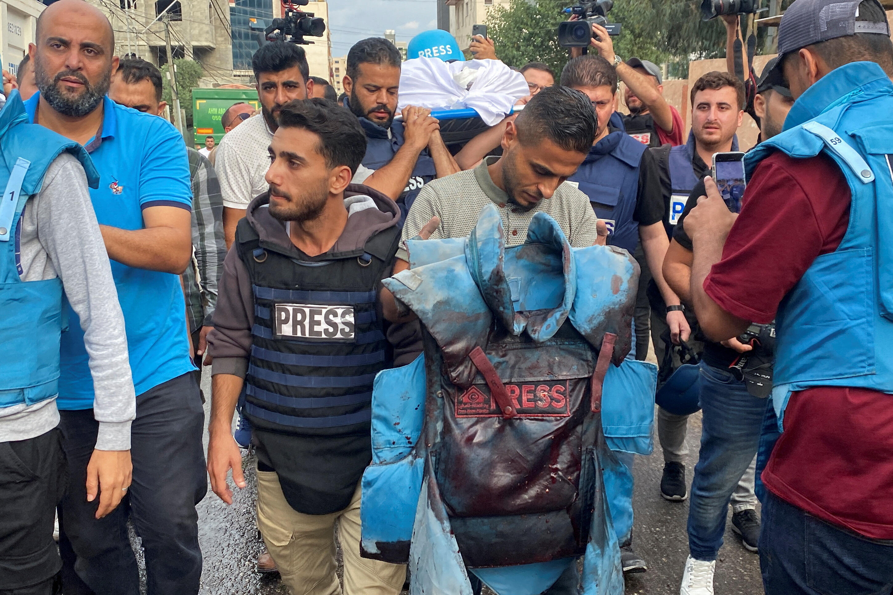 A colleague carries a blood-stained flak jacket belonging to Palestinian journalist Mohammed Soboh, who was killed along with two other journalists when an Israeli missile hit a building while they were outside reporting, at a hospital in Gaza City, October 1o, 2023. REUTERS/Arafat Barbakh