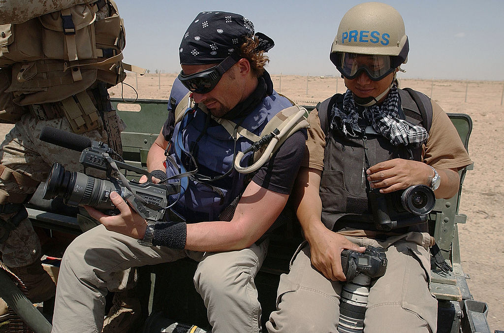 FALLUJAH, IRAQ - MAY 1, 2004: Embedded reporter Kevin Sites (L) of NBC and photographer Sung Su Cho of Time magazine ride in the back of a U.S. Marines vehicle to a checkpoint May 1, 2004 at the edge of Fallujah, Iraq. (Photo by Scott Peterson/Getty Images)