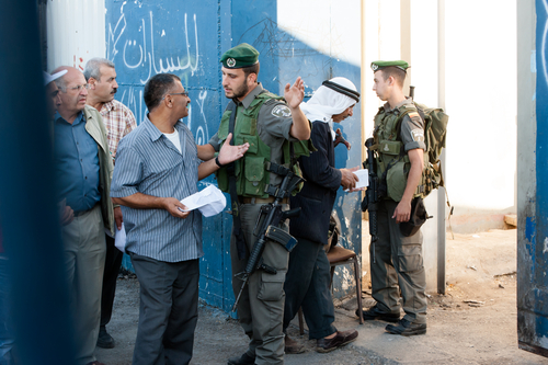 BETHLEHEM, PALESTINIAN TERRITORIES - AUGUST 17: Israeli soldiers check Palestinian men seeking access to Jerusalem at the Bethlehem checkpoint on the last Friday of Ramadan, West Bank, August 17, 2012