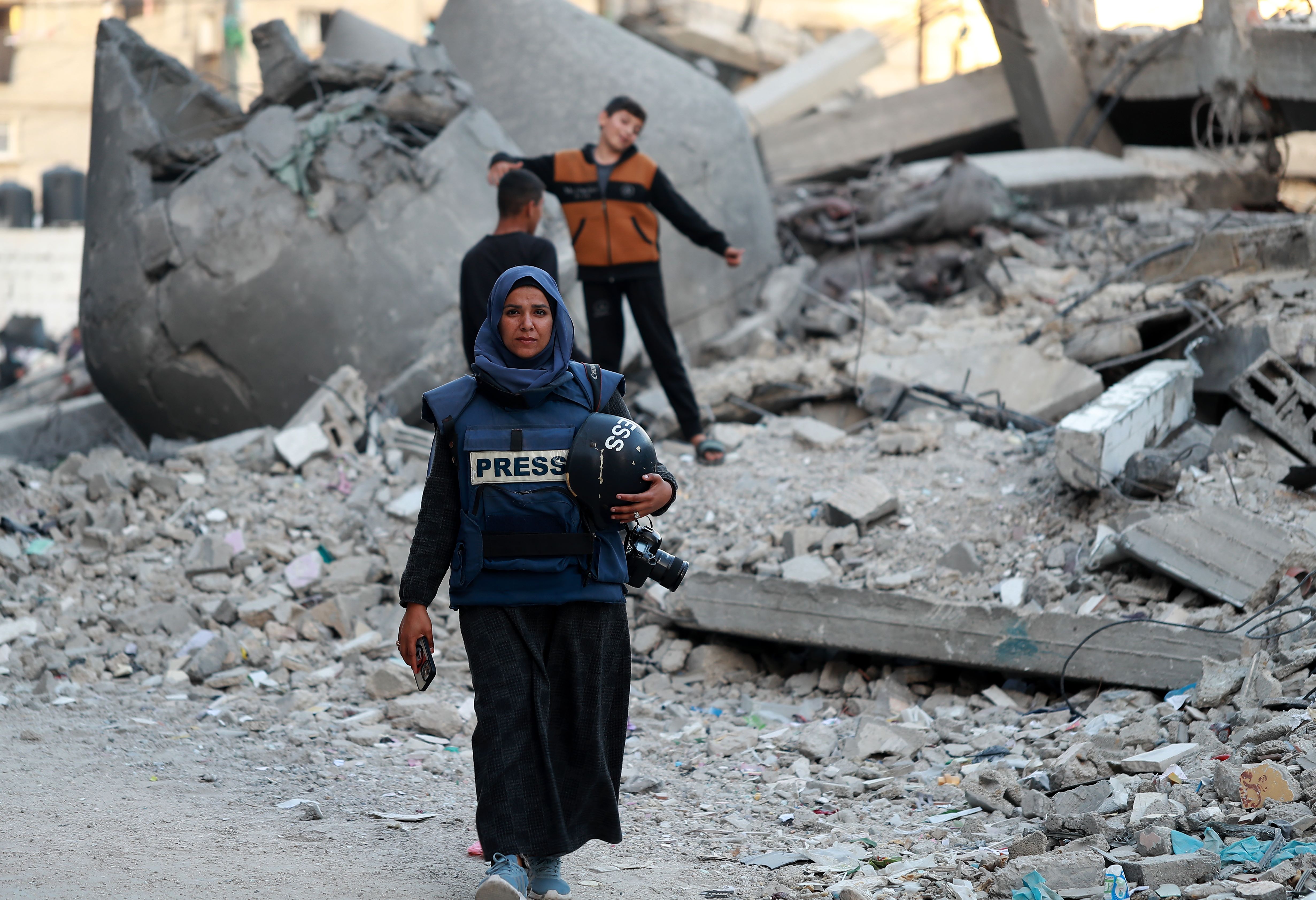 Female journalist walking through the rubble caused by Israeli bombardment in Gaza