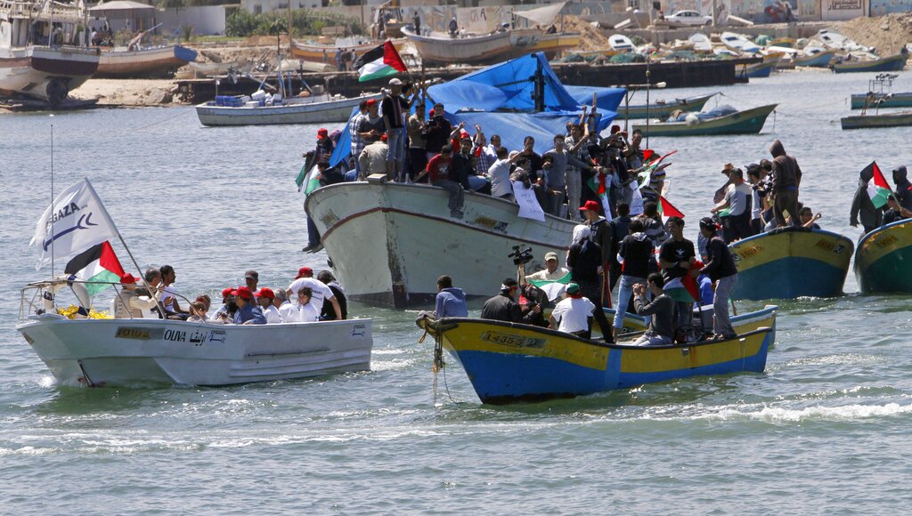 Palestinian and international activists sail on the "Oliva", bottom left, a human rights monitoring boat, in Gaza waters to observe routines of Palestinian fishermen within Palestinian waters on the Mediterranean sea, off the shore of Gaza City, Thursday, April 20, 2011. Activists accompanied Gaza fishermen within the 3-mile (5-kilometer) limit enforced by the Israeli navy.(AP Photo/Adel Hana)