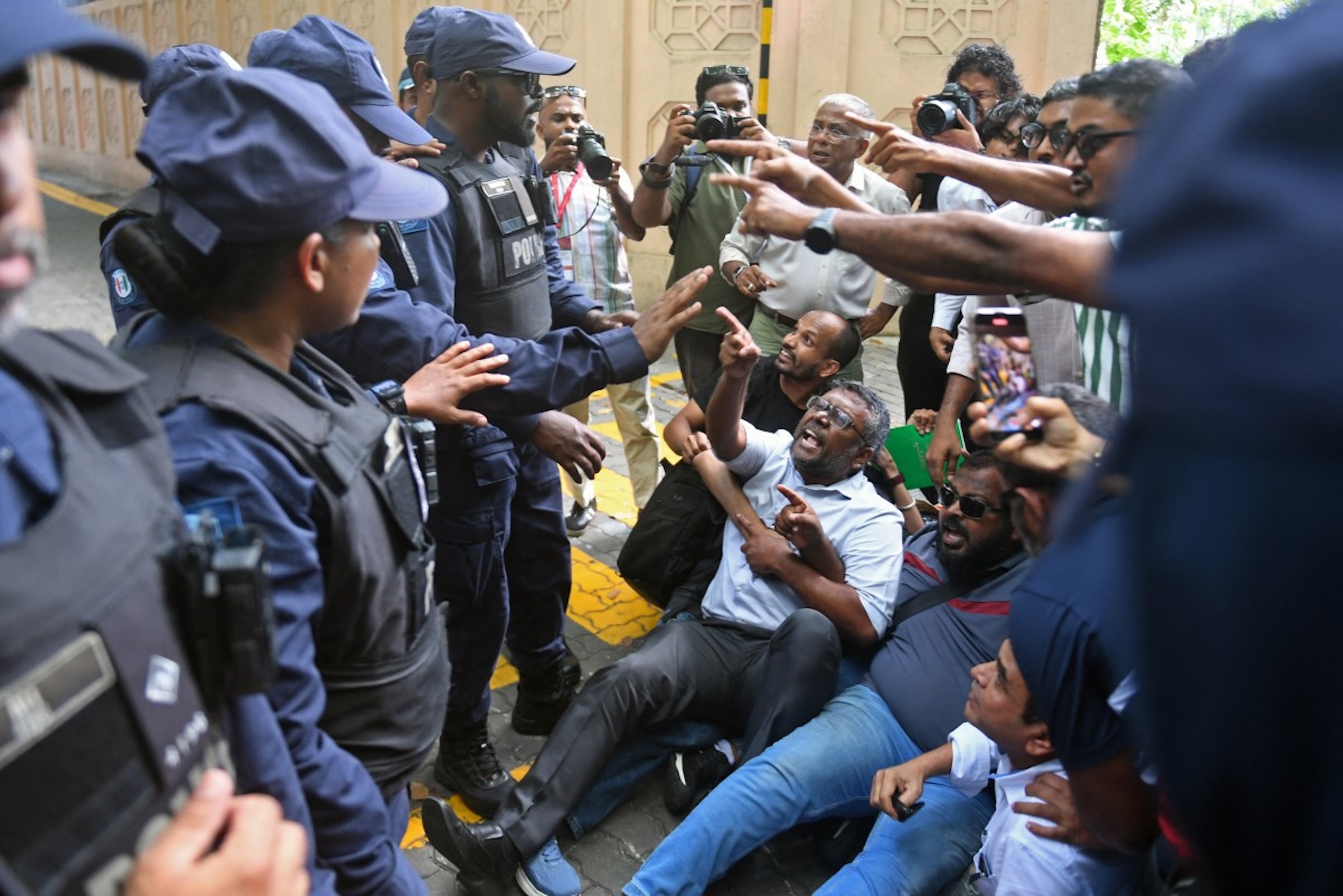 Members and supporters of Maldivian Democratic Party (MDP) shout slogans as police personnel stand guard during a protest outside the parliament in Male on September 16, 2025. 