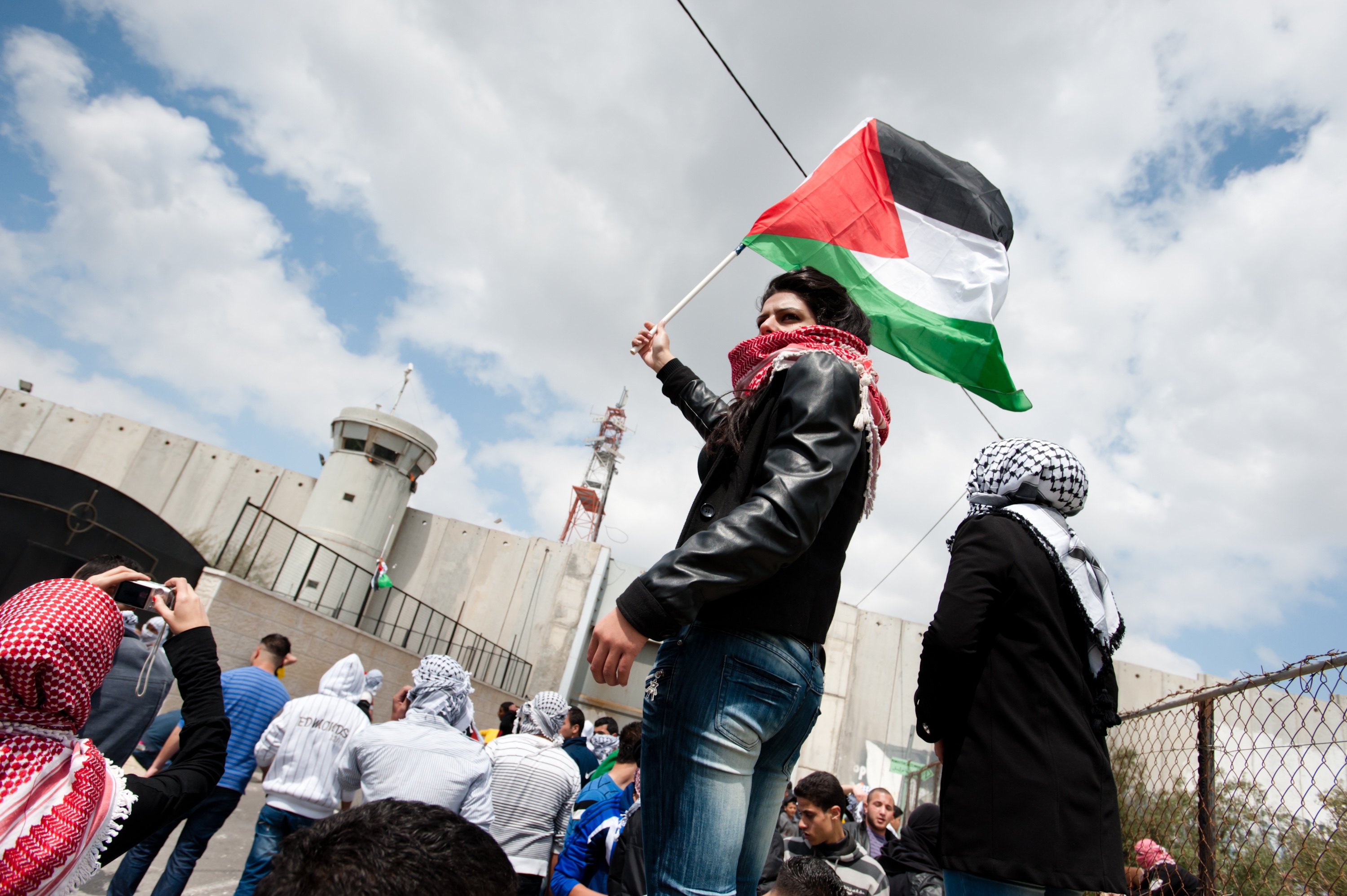 Bethlehem, Occupied Palestinian Territories - March 30, 2012: A Palestinian young woman waves a flag near the Bethlehem checkpoint during Land Day protests in Bethlehem.