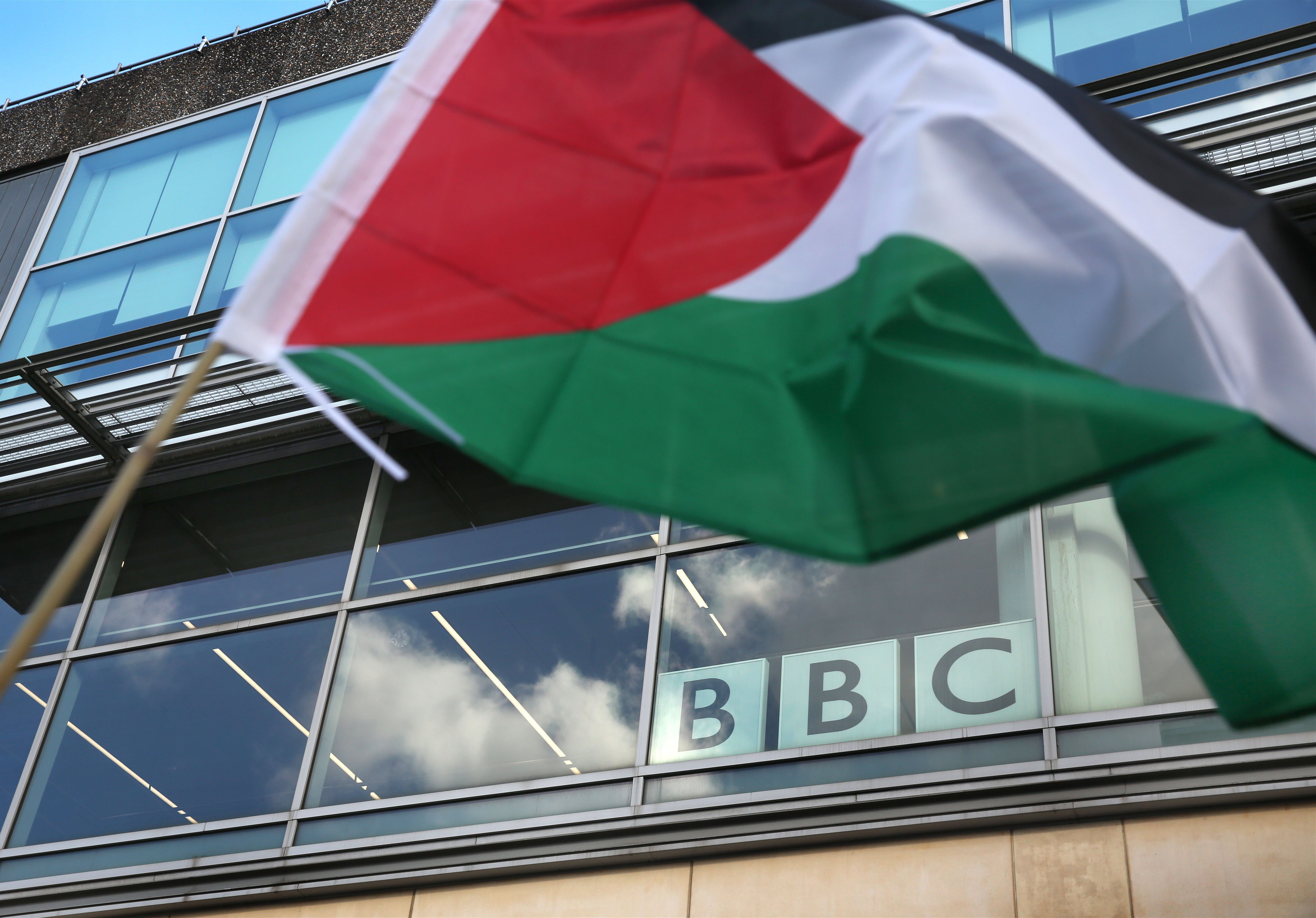 A demonstrator waves a Palestinian flag outside the BBC offices during a march protesting the network's coverage of the conflict in Gaza, with demonstrators accusing Western media of biased reporting and attempting to conceal the truth on the ground (Photo: Martin Pope/ZUMA Press Wire. Birmingham, England, Uk – Oct 2024)