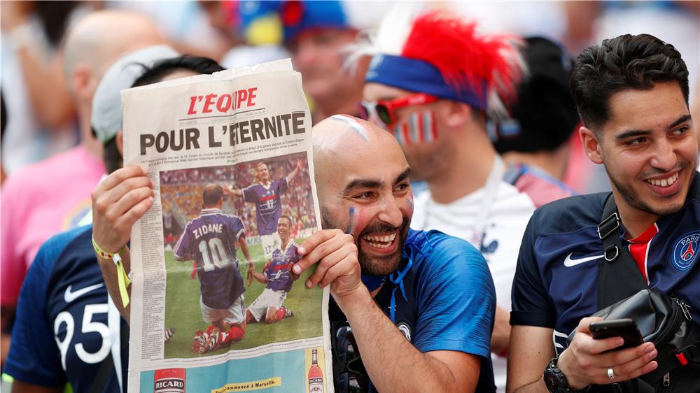مشجع للفريق الفرنسي يحمل صحيفة فرنسية ضمن مباراة فرنسا والأرجنتين، إذ ما زالت الصحف الورقية الرياضية تجذب الجمهور الرياضي في العصر الرقمي. تصوير: جون سيبلي – رويترز.