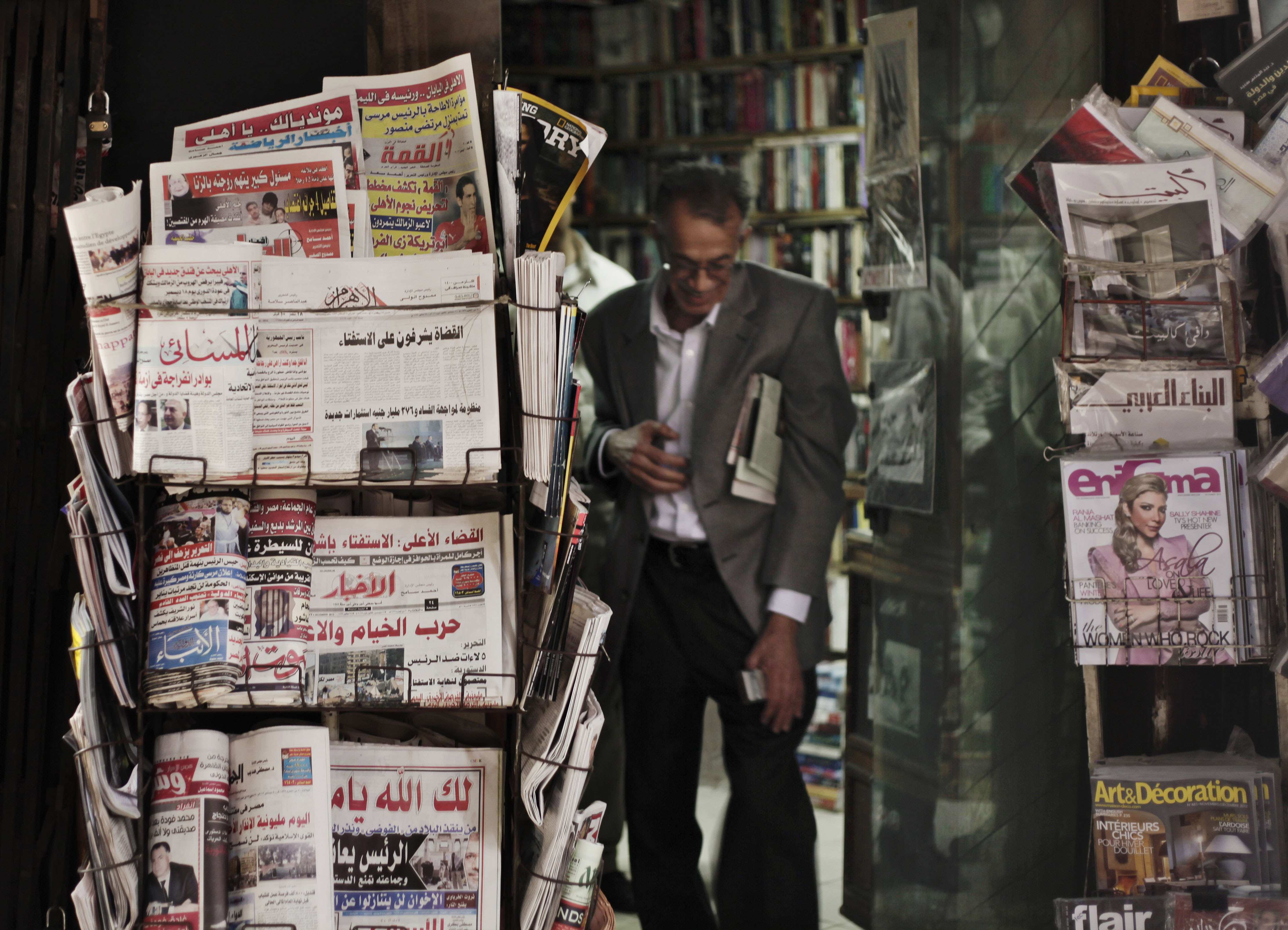An Egyptian walks past a stand displaying state-owned newspapers in Cairo, Egypt, Tuesday, Dec. 4, 2012