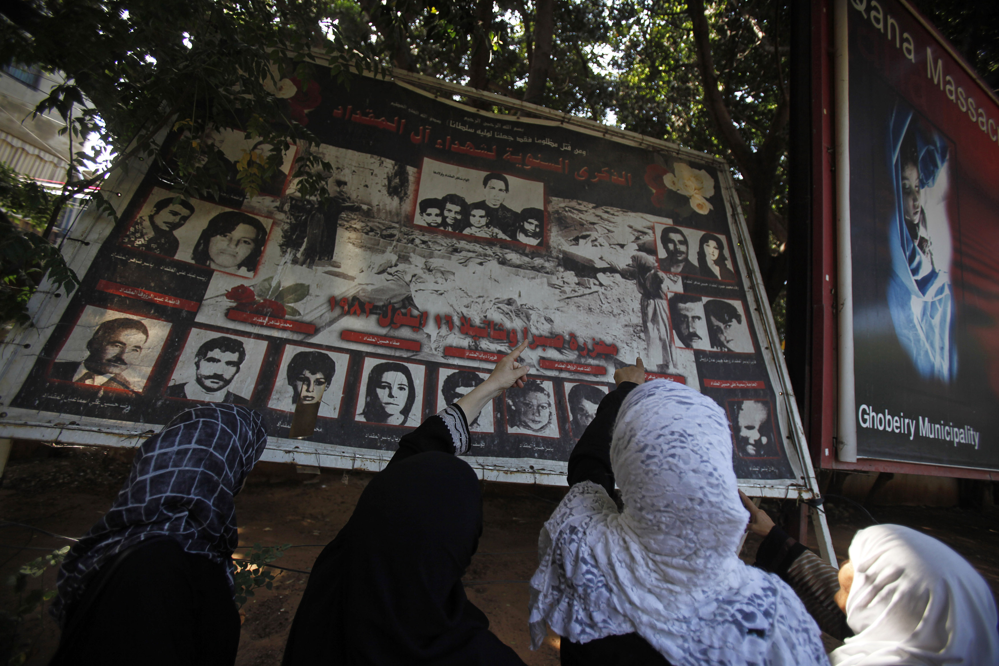 Palestinian women point at a poster depicting Palestinians who were killed during the Sabra and Shatila massacre in 1982, to mark the 28th anniversary of the massacre in Beirut, September 16, 2010. REUTERS/ Sharif Karim (LEBANON - Tags: CIVIL UNREST ANNIVERSARY)