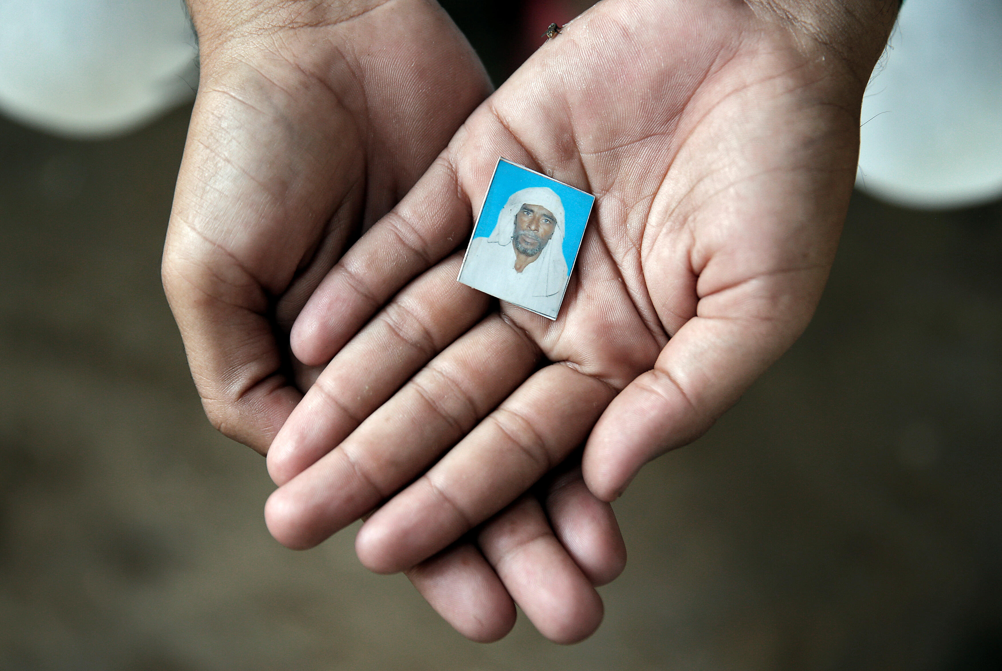 Irshad Khan, 24, holds a picture of his late father Pehlu, 55, in Jaisinghpur, India, June 2, 2017. Irshad survived an attack by cow vigilantes when transporting cattle which left his father dead and friends badly beaten. Picture taken June 2, 2017. To match Special Report INDIA-POLITICS/RELIGION-COWS REUTERS/Cathal McNaughton