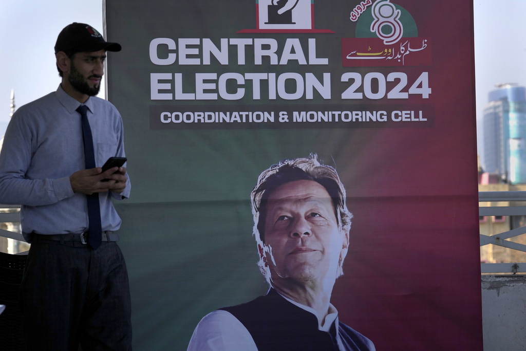 A supporter stands beside a poster of imprisoned leader Pakistan's Former Prime Minister Imran Khan display at his party office, in Islamabad, Pakistan, Friday, Feb. 9, 2024.