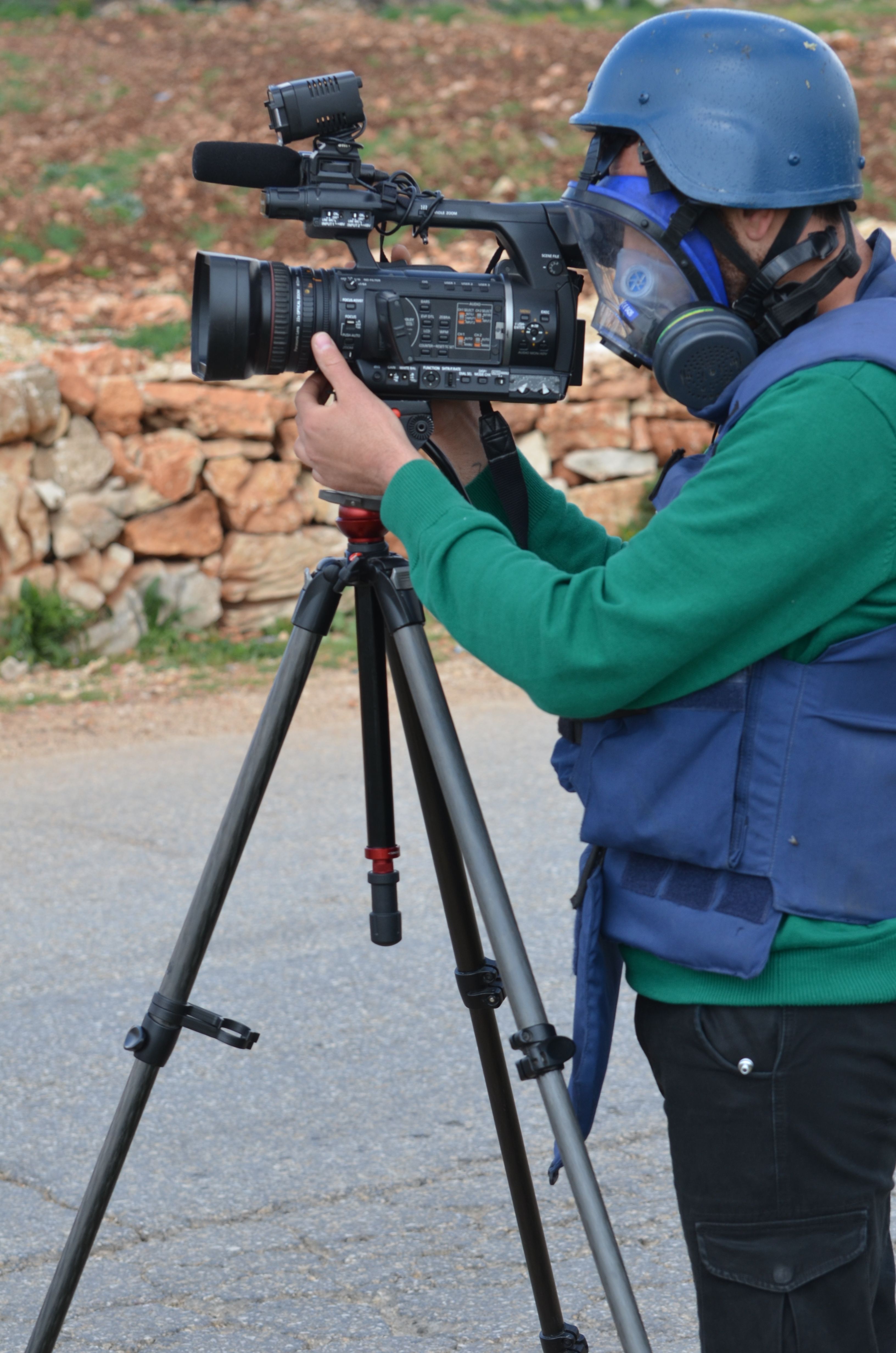 A Palestinian journalist aims the camera on a tripod to films the Friday protests in Nabi Saleh, West Bank, Palestine. 14/03/15
