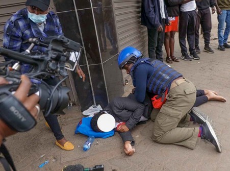 Okande drops the mic and administers first aid to an unconscious passerby who was struck by a tear gas canister. Photo: Okande via LinkedIn