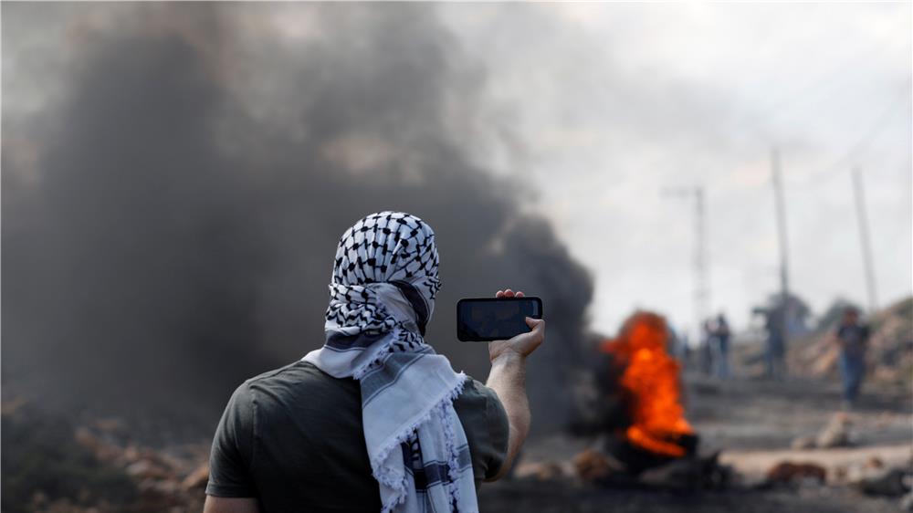محتج فلسطيني يأخذ صورة سيلفي خلال مواجهات مع القوات الإسرائيلية بالقرب من مستوطنة قدوم، قرب نابلس. تصوير: محمد توركمان - رويترز.