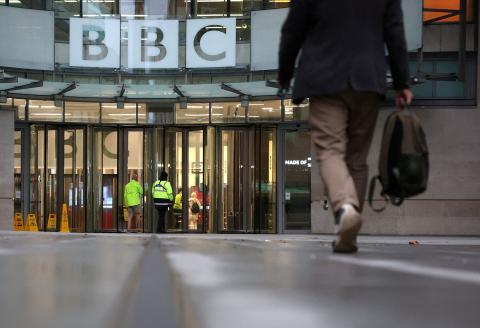 Image of Man approaching BBC entrance from behind, carrying a bag.