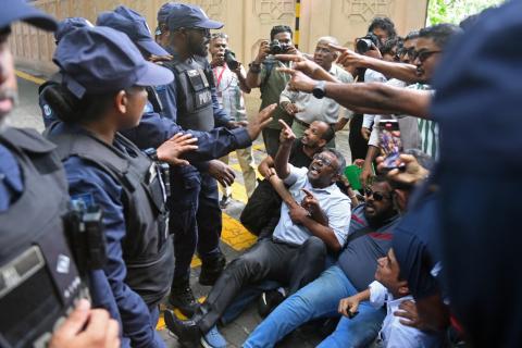 Members and supporters of Maldivian Democratic Party (MDP) shout slogans as police personnel stand guard during a protest outside the parliament in Male on September 16, 2025. 