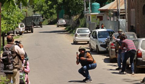 A video journalist covers himself during the exchange of gunfire between militants and Indian security forces in the Himalayan region of Jammu and Kashmir's Tral area on 15 May 2025