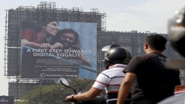 two men on a scooter, from the back. A huge ad poster in front of them. 