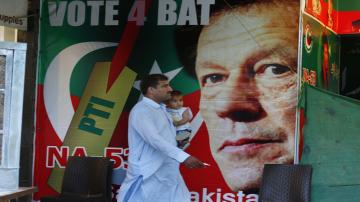 A Pakistani walks past a poster of Imran Khan, head of Pakistan Tehreek-e-Insaf party, at a market in Islamabad, Pakistan, Saturday, July 28, 2018. (AP Photo/Anjum Naveed)