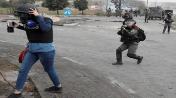 Israeli female soldier pointing a gun at a female journalist