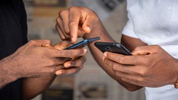 Two hands pointing at their mobile phones
