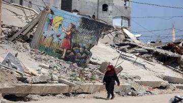 A woman walks past a colorful mural painted on the remains of a destroyed building in the Jabalia refugee camp. As images of conflict move from the frontlines to global exhibitions, the line between raw trauma and curated art becomes blurred.  (Photo: Majdi Fathi. Gaza, Palestine – April 2026)